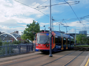 A Sheffield Supertram en bleu, orange et rouge Stagecoach livrée actuelle. Le tramway est montré traverser la jonction Park Square. Derrière ce est le pont reliant la jonction et les pistes du centre-ville de Sheffield. The whole square (now 20 years since redevelopment) is covered in trees and plants and new buildings can be seen beyond them.