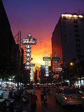 Une rue bordée au coucher du soleil avec de nombreux stands et boutiques avec beaucoup de panneaux portant thaïlandais et noms chinois