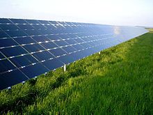 Les panneaux solaires, inclinés à environ 30 degrés, reflètent le ciel bleu au-dessus d'un terrain gazonné.