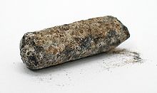 A, tige cylindrique noirâtre sérieusement émoussées, avec une vaste, l'effritement la corrosion brun et blanc
