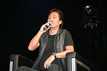 Un homme assis sur une chaise et en parlant dans un microphone