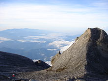 Une vue de la crête de basse, avec un pic plus petit à droite de la photo, avec des montagnes boisées à l'arrière-plan