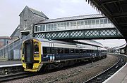 Un train de deux coach sous un pont en treillis
