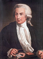 Peinture d'un homme d'âge moyen assis près de la table, portant une perruque, veste noire, chemise blanche et foulard blanc.