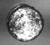 Un très petit disque de métal argenté, agrandie pour montrer sa texture métallique