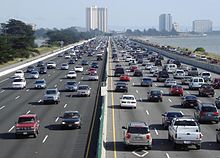 Regardant vers le bas une ligne droite occupée dix voies l'autoroute le long d'une côte. Dans le fond sont quelques immeubles à plusieurs étages.