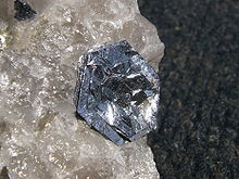 Lustré, argentés, plat, cristaux hexagonaux dans les couches plus ou moins parallèles se asseoir en fleur sur une rugueuse, translucide morceau de quartz cristallin.