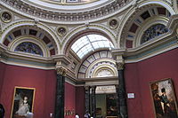Pièce octogonale avec un riche fond d'écran rouge, peintures et les détails architecturaux en marbre de différentes couleurs