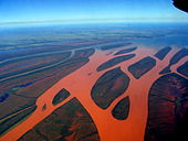 Photo aérienne d'une rivière fourchue qui a viré au rouge à cause du ruissellement du sol rouge.