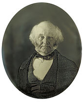 Demi-longueur portrait photographique de, un homme chauve personnes âgées vêtu d'un manteau noir, gilet et cravate