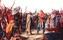 Un groupe de guerriers en costume médiéval entourent deux hommes dont les postures suggérer qu'ils sont sur le point d'embrasser. L'homme sur la droite est plus grand, a les cheveux longs juste et porte une tunique rouge vif. L'homme sur la gauche de sa calvitie avec les cheveux courts gris et une barbe blanche. Il porte un long manteau brun.