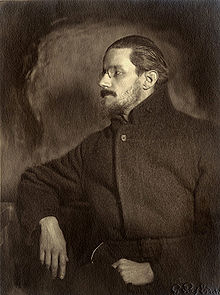 Demi-longueur Portrait d'un homme dans la trentaine. Il regarde à sa droite pour que son visage est de profil. Il a une moustache, une barbe fine et cheveux mi-longs plaqués en arrière, et porte un pince-nez et un manteau sombre plaine, regardant vaguement comme un révolutionnaire russe.