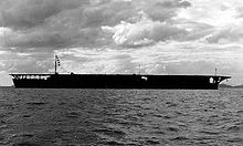 Porte-avions sur la mer avec ciel nuageux en arrière-plan.