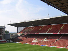 Une tribune dans un stade de sport. Les sièges sont à dominante rouge.
