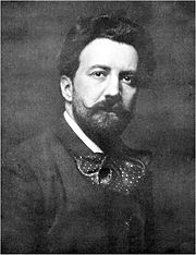 Cabeza y los hombros retrato de un hombre joven con el pelo que fluye largo medio oscuro, una barba y bigote, y una enorme pajarita disquete