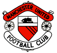 Una cresta de fútbol. En el centro está un escudo con un barco a toda vela sobre un campo rojo con tres líneas negras diagonales. A cada lado de la pantalla son dos rosas estilizadas, que separan dos pergaminos. El desplazamiento superior es de color rojo y lee
