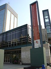 El Centro Francis Winspear de música con una pancarta delante de la torre de Edmonton Orquesta Sinfónica y Century Place detrás de él.