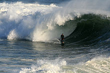 Foto de la persona que practica surf en la parte inferior de la ola, tratando de dejar tubo envolverlo