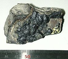 Un gris pieza 5 centímetros brillante de la materia con una superficie rugosa.