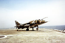 Un Harrier en la cubierta de un portaaviones pequeño, con su rueda de proa de la cubierta